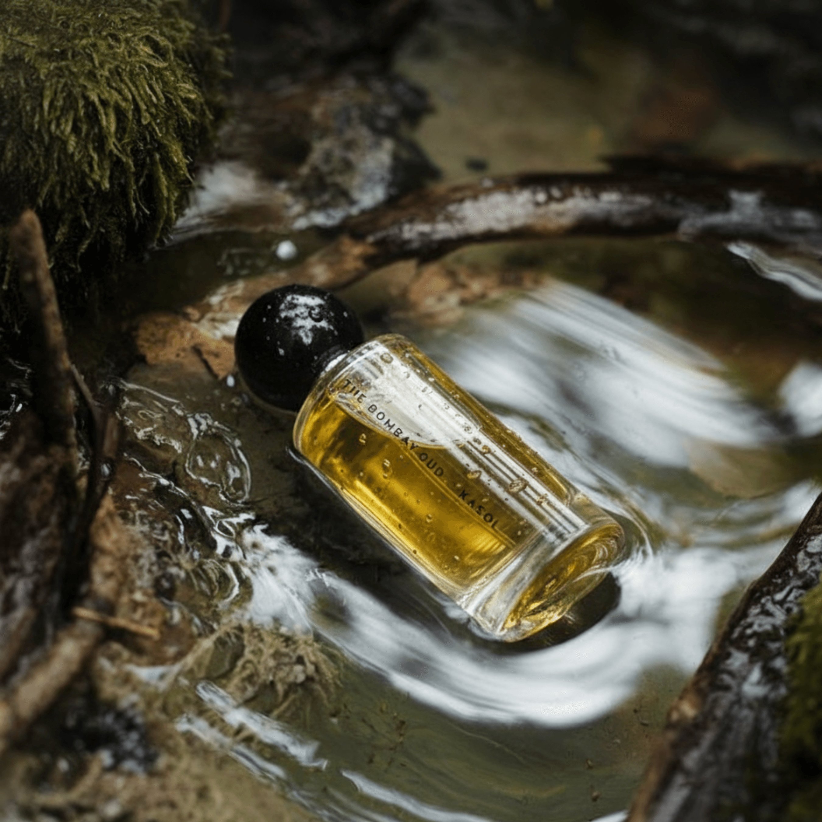 Kasol 60ml perfume lying in a forest stream, emphasizing its natural, earthy scent profile with cannabis and patchouli accords.