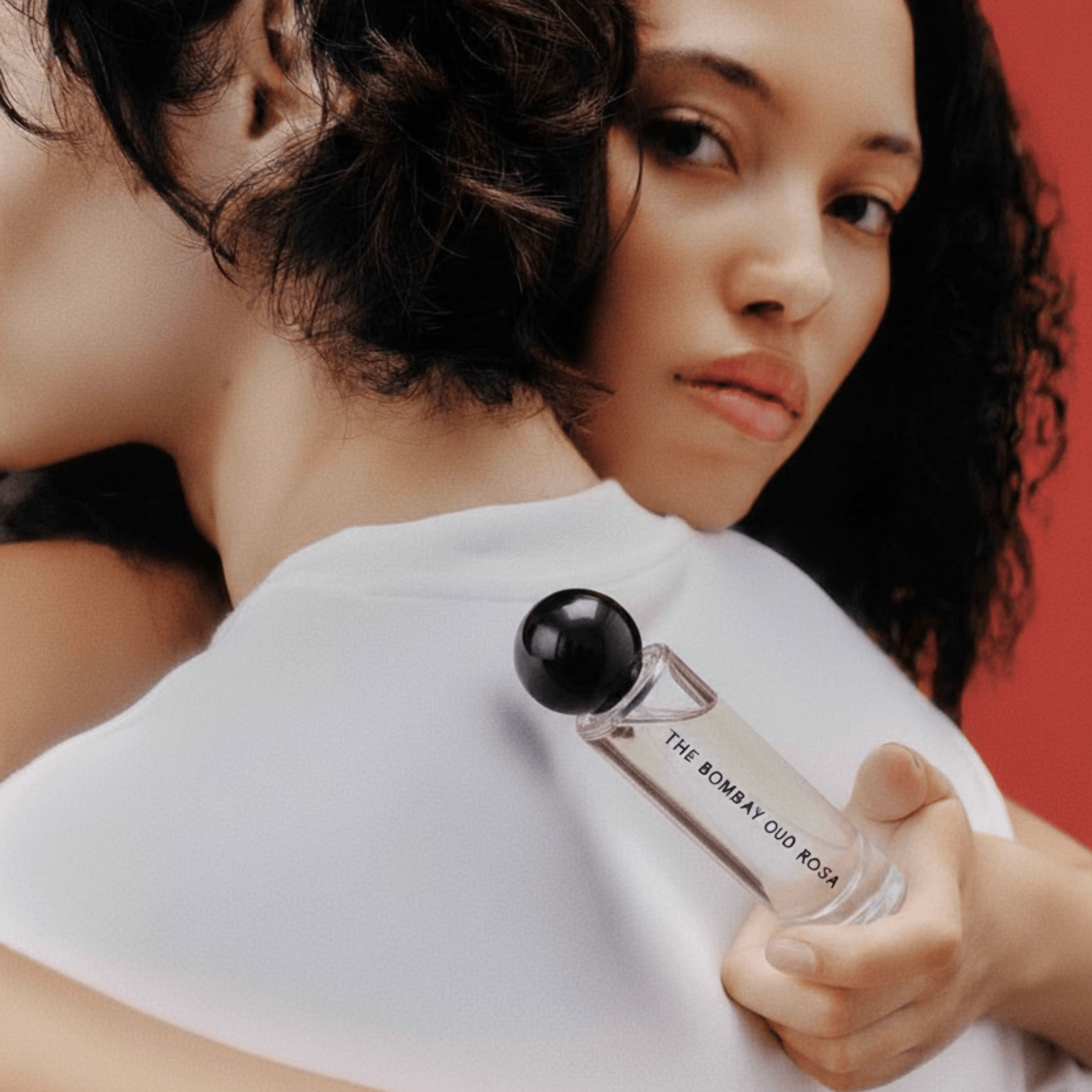 Rosa 60ml perfume held by a woman embracing a partner, highlighting its romantic and intimate floral scent. A sensual addition to personal care.