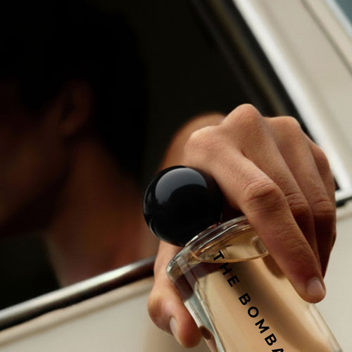 Close-up of hand holding Boond 60ml perfume bottle from a car window, emphasizing its sleek design and personal luxury appeal.