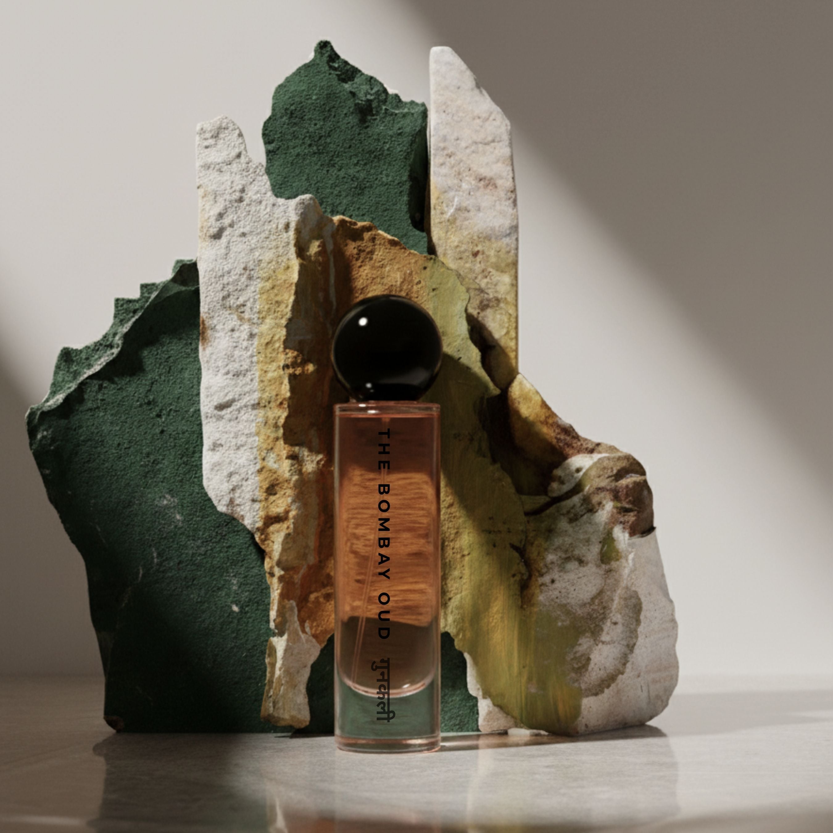 Gunkali 60ml perfume from The Bombay Oud displayed against artistic stone backdrop, highlighting its premium fragrance appeal.