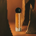 Royal Oud 60ml perfume showcased in a warm, artistic setting with sculptural elements, highlighting its rich, woody scent profile.