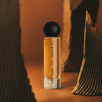 Royal Oud 60ml perfume showcased in a warm, artistic setting with sculptural elements, highlighting its rich, woody scent profile.